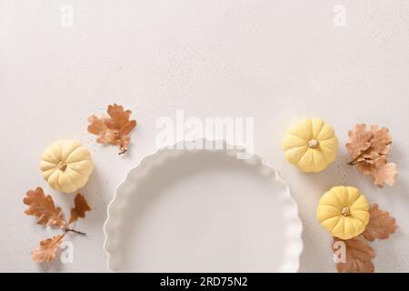 Autumn frame with pumpkins, fall leaves, empty baking dish. Concept cook Pumpkin pie on white background. Thanksgiving Day. View from above. Stock Photo