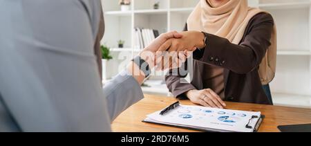 Two hijab Asian women shaking hands after a startup company meeting. run by a young, talented woman. The management concept runs the company to grow Stock Photo