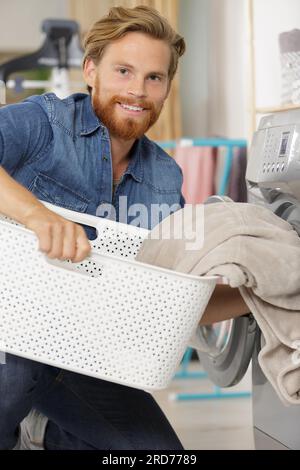 happy man taking clothes from drying machine Stock Photo