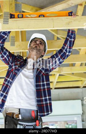 builder using spirit level on roof beam Stock Photo