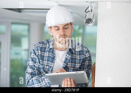 contractor using tablet by security camera Stock Photo