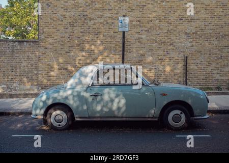 Blue green Nissan Figaro car parked outside in Notting Hill London in dappled sunlight Stock Photo
