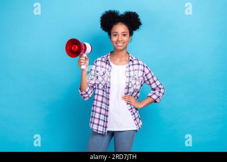 Photo of cheerful sweet lady wear plaid shirt rising bullhorn making announcement isolated blue color background Stock Photo