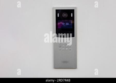 Doorbell with video camera and microphone, on the white wall of an apartment building, doorbell camera. Stock Photo