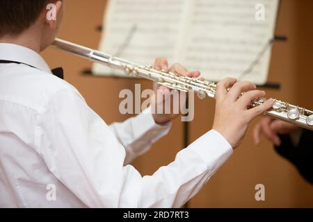 The boy plays the shining flute. Wind musical instrument. Stock Photo