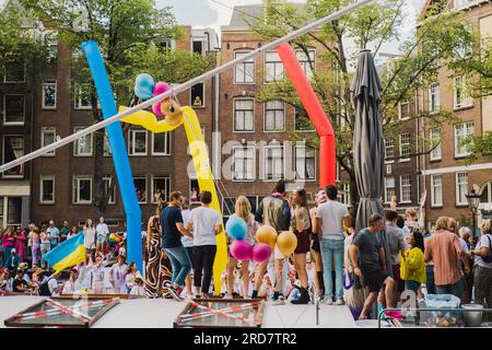 Amsterdam, North Holland, Netherlands – August 6, 2022: A crowd of people standing on a houseboat celebrates Pride Amsterdam surrounded with festive b Stock Photo