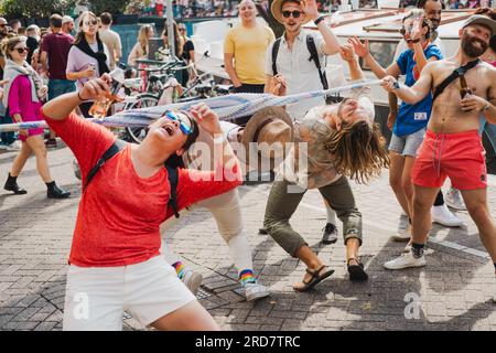 Amsterdam, North Holland, Netherlands – August 6, 2022: Bystanders do impromptu limbo dance on the streets of city celebrating Pride parade Stock Photo