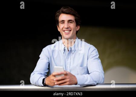 Portrait of cheerful young man in formal using smartphone Stock Photo