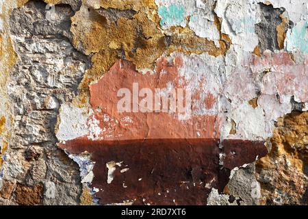 Old colorful scabrous uneven damaged repairing wall painted surface as background front view abstract photo close up Stock Photo