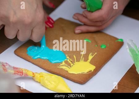 Hand draws on gingerbread with cream icing. Stock Photo