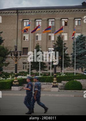 Two soldiers seen walking past a row of Karabakh flags lining outside the Presidential Building in Stepanakert, Nagorno-Karabakh. The unrecognised yet de facto independent country in South Caucasus, Nagorno-Karabakh (also known as Artsakh) has been in the longest-running territorial dispute between Azerbaijan and Armenia in post-Soviet Eurasia since the collapse of Soviet Union. It is mainly populated by ethnic Armenians. Stock Photo