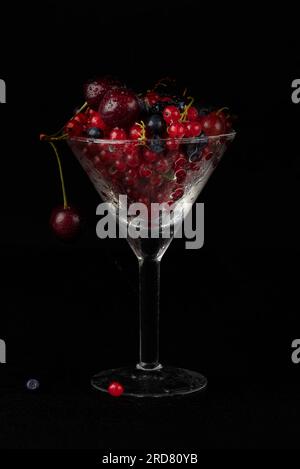 Summer berries in a glass glass on a dark background. Stock Photo