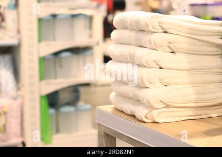 White towels folded in a pile in a store close-up. Home textile beautiful towels stacked on a shelf in a store Stock Photo