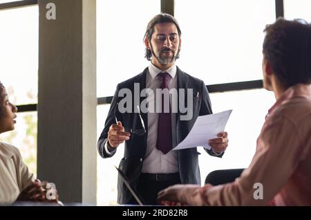 Serious businessman talk to diverse business people Stock Photo