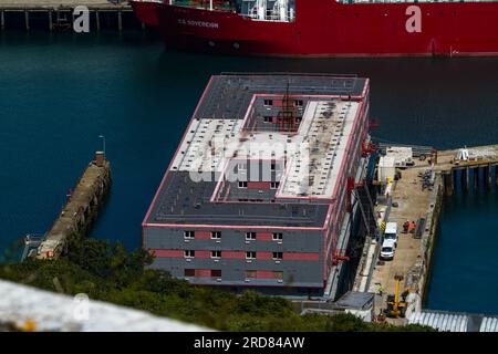 PORTLAND, ENGLAND – JUL 20  2023: Bibby Stockholm barge from above docked on land after arriving the day before, defocussed wall in foreground.  To ho Stock Photo