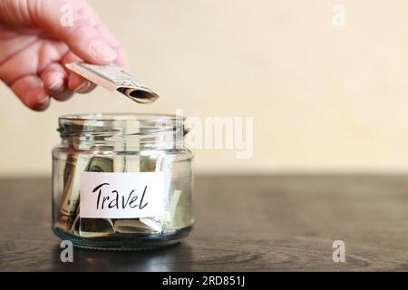 Piggy bank with dollars for travel. Accumulation of financial concept. Glass jar with money. The woman puts more money in the piggy bank Stock Photo