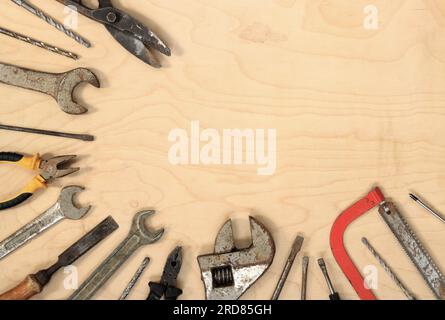 Old tools on a light wooden background, top view. Wrenches, pliers, metal drills, saws and screwdrivers. Tools and empty space Stock Photo