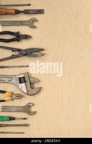Tools for different repair work, top view. Old tools are laid out in a row on a light wooden table and empty space for text Stock Photo