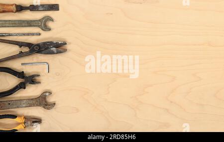 Tools for different repair work, top view. Old tools are laid out in a row on a light wooden table and empty space for text Stock Photo