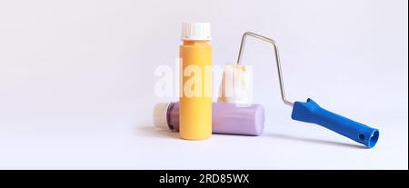 Interior renovation paint. Paint in plastic bottles and paint roller on a white background. Free space for text. Two bottles of acrylic paint, photo f Stock Photo