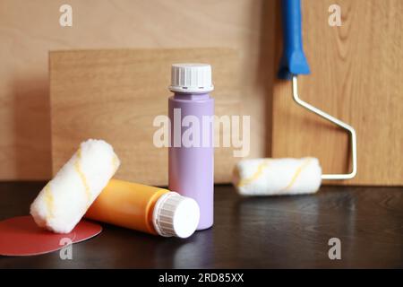 Two bottles of acrylic paint on a wooden table. Items needed for repair. Repair paints, rubber gloves, sandpaper and wood planks Stock Photo