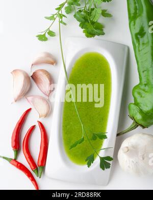 Top view of a bowl of salsa verde with ingredients: cilantro, chili peppers, bell pepper and garlic Stock Photo