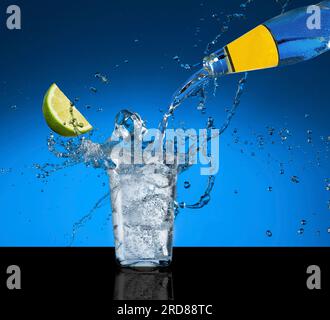 Glass with tonic and lime. Splashed tonic water in a glass. Stock Photo