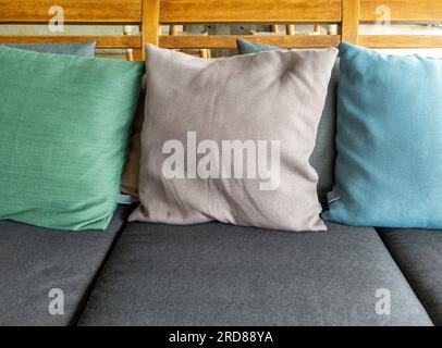 The soft textile cushion in the pastel color on the gray textile sofa in the living room of the modern house, front view with the copy space. Stock Photo