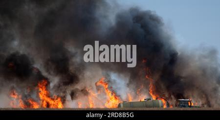 Leipzig, Germany. 19th July, 2023. Dark clouds of smoke rise from a field fire near Leipzig. A slurry tanker extinguishes with water. Credit: Ralf Hirschberger/dpa/Alamy Live News Stock Photo