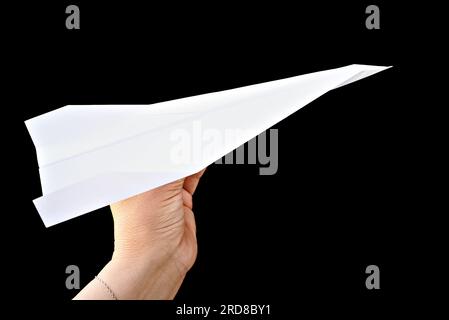 Woman's hand holding paper plane on black background Stock Photo