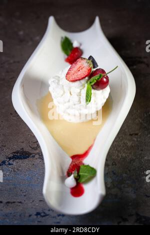 sweet meringue dessert with strawberry berries close-up on a dark background. Stock Photo