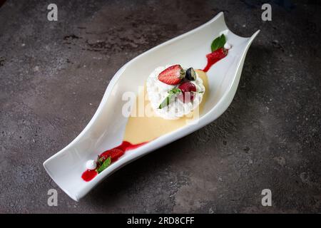 top view meringue dessert with strawberries on a dark concrete background. Stock Photo