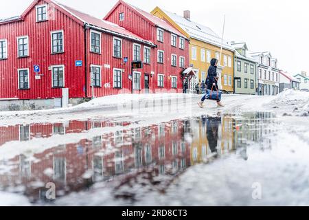 Tourist walking near the multicolored houses of Tromso in winter, Tromso, Norway, Scandinavia, Europe Stock Photo