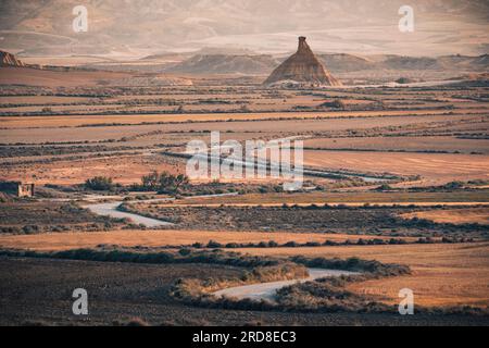 The badlands of Bardenas Reales at sunrise with a winding road leading towards the Castildetierra rock formation, Navarre, Spain, Europe Stock Photo