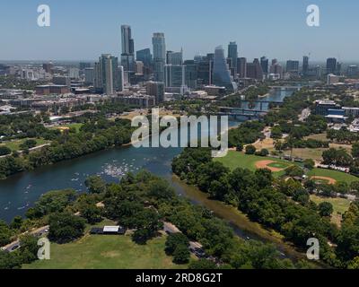 The skyscrapers of Austin, Texas are shown with the Colorado River / Lady Bird Lake visible in the foreground during a summer day from an aerial view. Stock Photo