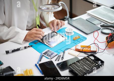 Technician using tweezers when repairing smartphone Stock Photo
