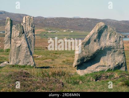 Standing stones with the tranquil waters of Loch Ceann Huabhig and cottages in the background on the west coast of the Isle of Lewis in the Outer Hedr Stock Photo