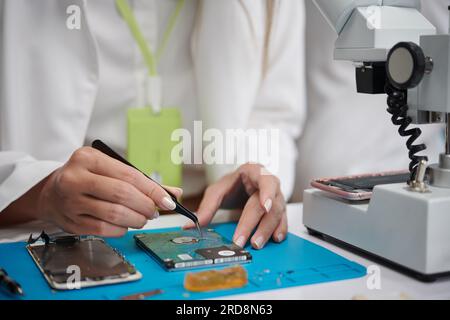 Closeup image of technician using tweezers with repairing electronics Stock Photo