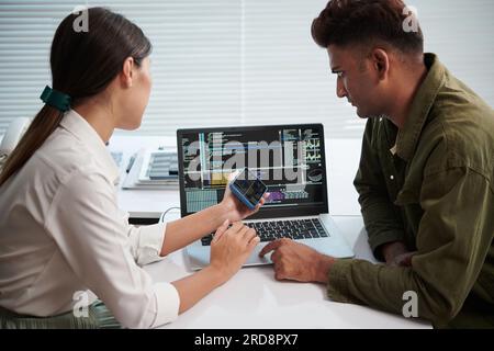 Repairing serving worker using special software to check if smartphone is tracker, tapped or monitored by spy software Stock Photo