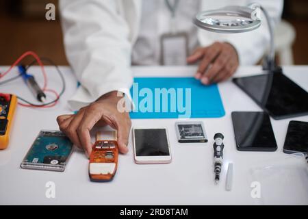 Closeup image of technician reparing feature phone,smartphone and hard drive, selective focus Stock Photo