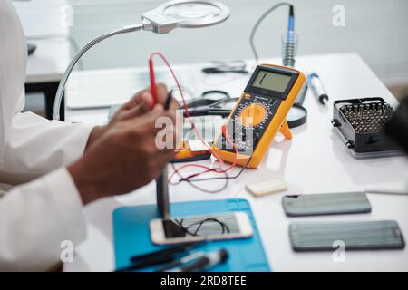 Engineer using multimeter when examining if smartphone works good after repairing Stock Photo