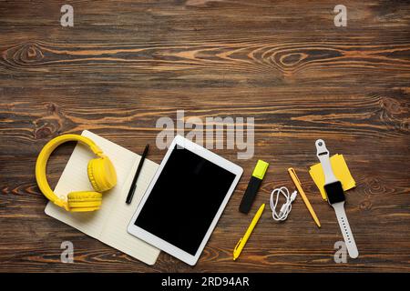 Composition with modern tablet computer, headphones, wristwatch and stationery on wooden background Stock Photo