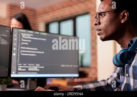System engineer typing machine learning server code on computer, sitting at desk in software company. Programming engineer working on database system with coding script in it security agency. Stock Photo