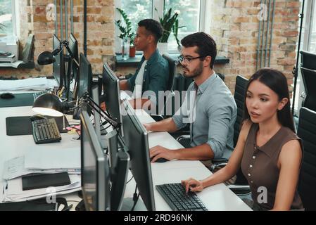 Teamwork . Group of young employees working on computers while sitting in modern open space Stock Photo