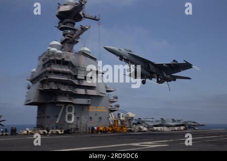 An F/A-18E Super Hornet, attached to the 'Tomcatters' of Strike Fighter Squadron (VFA) 31, passes over the worldÕs largest aircraft carrier USS Gerald R. FordÕs (CVN 78) flight deck, July 14, 2023. The Gerald R. Ford Carrier Strike Group is participating in Neptune Strike, a multiyear effort focused on harmonizing U.S. and NATO planning teams to transfer command and control of Allied naval and amphibious forces to STRIKFORNATO, to provide assurance, deterrence, and collective defense for the Alliance. (U.S. Navy photo by Mass Communication Specialist 2nd Class Jacob Mattingly) Stock Photo