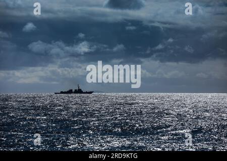 Silhouetted on the horizon one of the mainstay of the US Navy escort fleet an Aerleigh Burke class destroyer, with 90 planned and over 70 in service Stock Photo