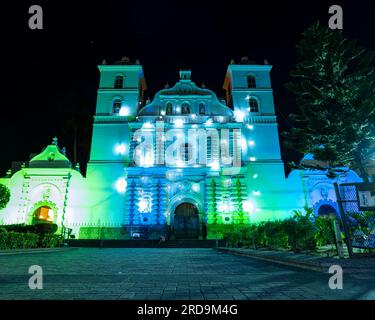 Tegucigalpa, Francisco Morazan, Honduras - December 11, 2022: Tegucigalpa Cathedral and Park at Night Lit by Blue and Green Lights with Woman Sleeping Stock Photo