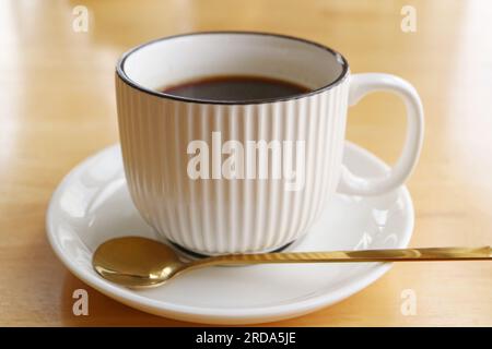 Cup of black coffee with spoon isolated on wooden table Stock Photo