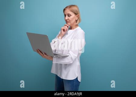 serious adult woman with blond hair working remotely using laptop Stock Photo