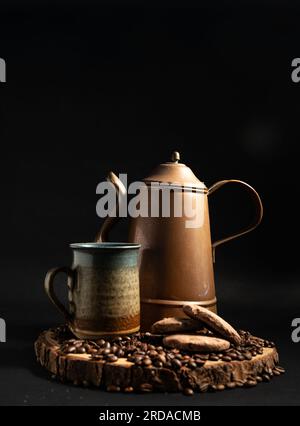 A copper coffee pot, ceramic mug, coffee beans and biscuits. Stock Photo